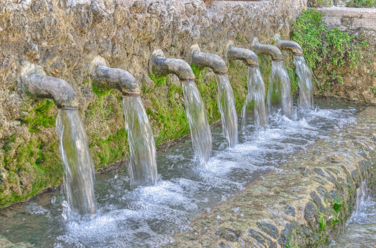 Fountain with seven faucets. Water falling down strongly. Natural and fresh color.