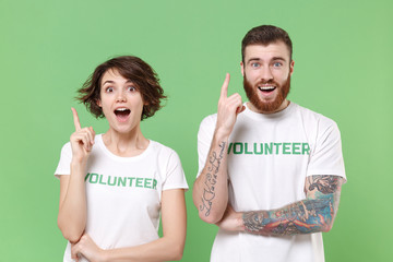 Excited two friends couple in white volunteer t-shirt isolated on pastel green background....