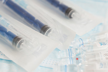 Sterile medical blue masks, syringes, vials with vaccine and analogue thermometer on white background.