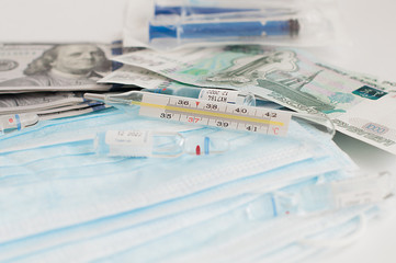US dollars and Russian roubles banqnotes with sterile medical blue masks, syringes, vials with vaccine and thermometer