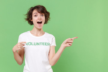 Excited young brunette woman in white volunteer t-shirt isolated on pastel green background in...