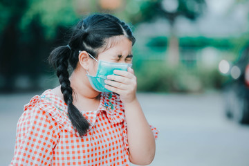 An Asian girl wearing a Corona protective mask , An Asian girl has a cough with phlegm. , Asian children wear medical masks to protect PM 2.5