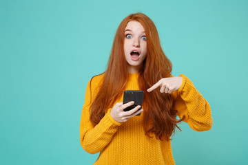 Shocked young redhead woman girl in yellow sweater posing isolated on blue turquoise background...