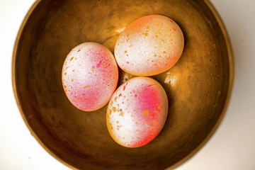 Hand painted easter eggs in golden metal bowl pink orange shiny colored paint pattern © Maciek