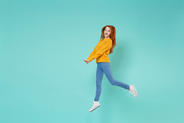 Fototapeta na wymiar Pretty young redhead woman girl in yellow knitted sweater posing isolated on blue turquoise wall background studio portrait. People emotions lifestyle concept. Mock up copy space. Jumping having fun.