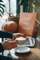 A freelancer works at a laptop and drinks coffee in a cafe
