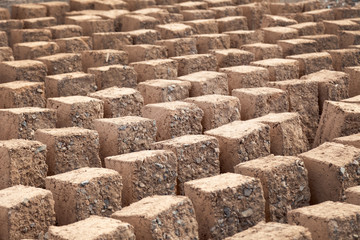 Traditional homemade production of raw clay brick laid out in stacks for drying on brick factory