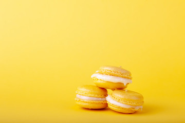 Three yellow lemon macaroon in pile on yellow background