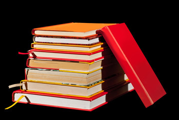 Many hardcover books on black background. Stack of books with white and yellow pages.