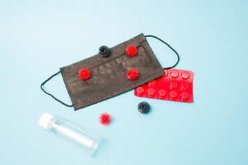 virus models on a black medical protective mask, antiseptic bottle, pills in red bluster, blue background, copy space, coronavirus 2020, top view
