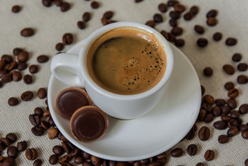 A cup of strong coffee. Coffee in a white cup on a saucer. Coffee beans.