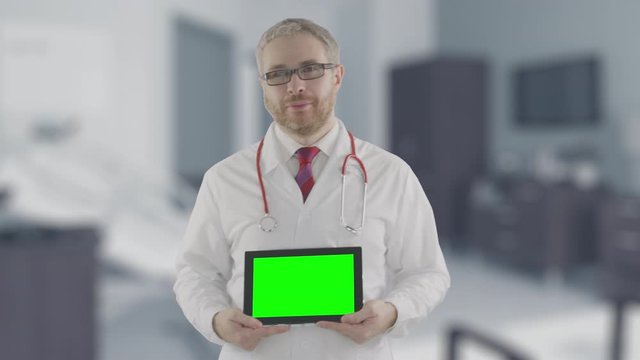 Portrait of a confident doctor holding modern tablet PC with green screen, shot on Red camera. Alpha matte for picture or video placement