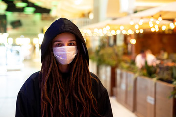 girl in a medical mask in a black hood at the mall