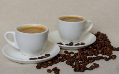 Two cups of fresh espresso with coffee beans. Sprinkled coffee beans. Morning coffee concept
