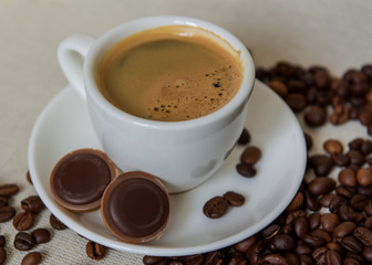 A cup of strong coffee. Coffee in a white cup on a saucer. Coffee beans.