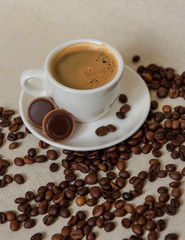 A cup of strong coffee. Coffee in a white cup on a saucer. Coffee beans.