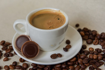 Latte coffee / cappuccino in a transparent glass with a pen on a wooden background. Coffee beans. Chocolate candies with nuts. Morning coffee concept.