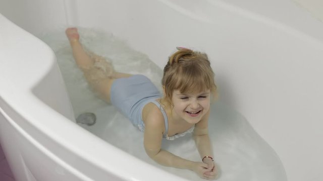 Cute blonde girl takes a bath in swimwear. Little child, 4 years old. Hygiene