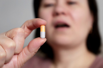 Woman takes a pill, girl putting capsule in open mouth. Sick female taking medicines, concept of antibiotic, vitamin, coronavirus prevention