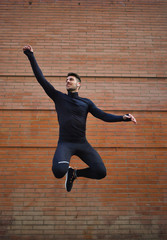 Hombre joven saltando al aire libre vistiendo un conjunto negro deportivo