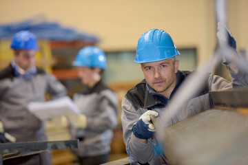 Middle aged factory worker positioning a metal bar