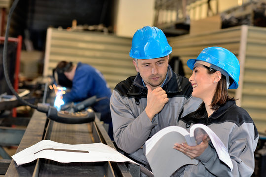 Unsure Male Worker Is Looking At Happy Female Engineer Notes