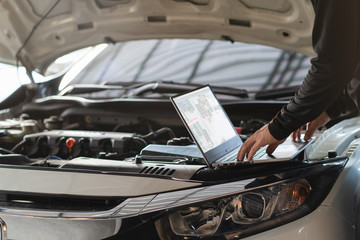 Professional mechanic man using laptop computer to solve troubleshooting problem of the car