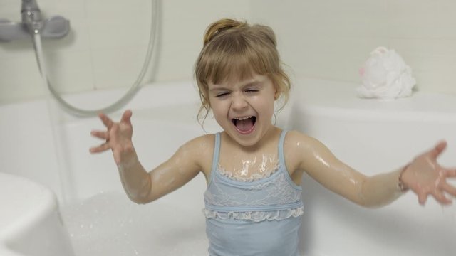 Cute blonde girl takes a bath in swimwear. Little child, 4 years old. Hygiene