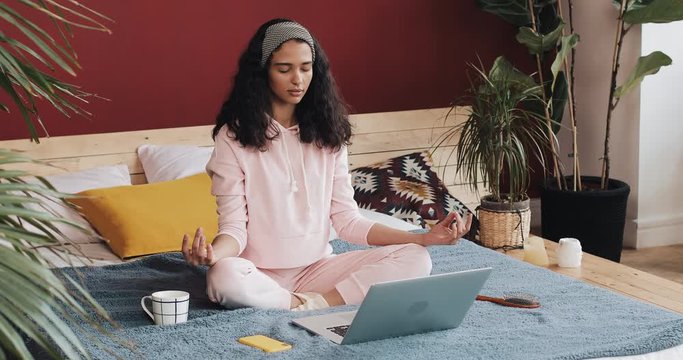 Beautiful young african american woman doing yoga exercise and watching tutorial lesson on laptop computer at home
