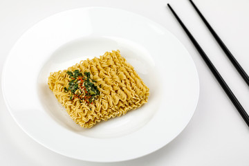 dry instant noodle on plate with chopsticks isolated on white background