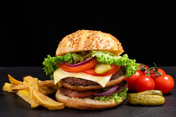 Big burger with french fries on dark background