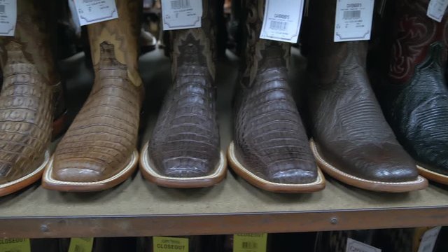Traditional American leather Cowboy boots, Western style, rodeo market and riding gear on display. American lifestyle concept. American-style boots from ostrich, crocodile and buffalo leather.