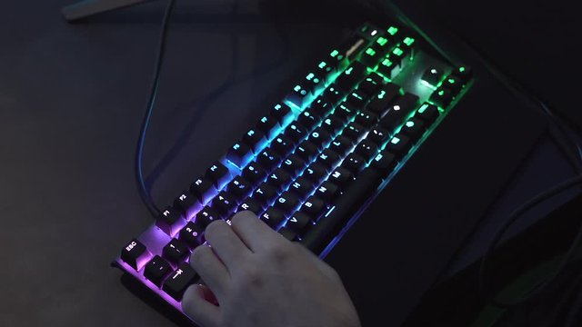 Rotating closeup shot of professional gamer hands playing on keyboard in dark room. Kyber sport concept