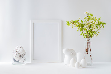 Home interior with easter decor. Mockup with a white frame and spring flowers in a vases on a light...