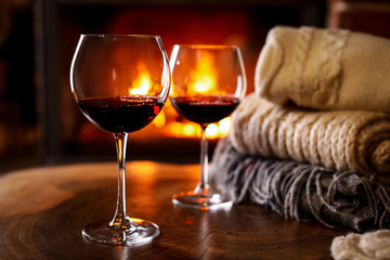 Glasses of wine, knitwear and blurred fireplace on background