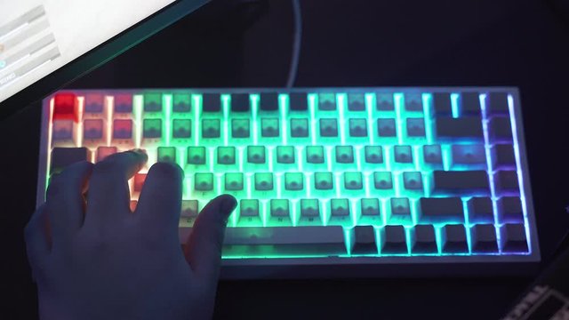 Closeup shot of professional gamer hands playing on keyboard in dark room. Kyber sport concept