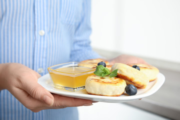Woman with plate of delicious cottage cheese pancakes, closeup