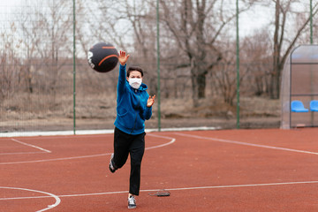 Fototapeta premium A young woman is playing sports on a sports field in a mask. Protection from coronavirus infection with a medical mask.