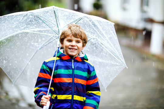 Beautiful Little Kid Boy On Way To School Walking During Sleet, Rain And Snow With An Umbrella On Cold Day. Happy And Joyful Child In Colorful Fashion Casual Clothes.