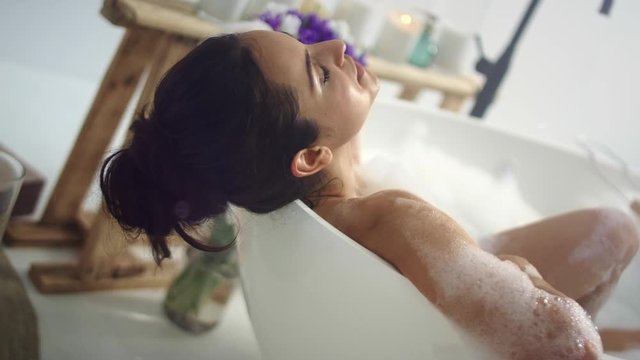 Closeup romantic woman taking bath at home. Sensual girl relaxing in foam bath.