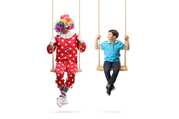 Clown and a boy swinging on swings and looking at eachother