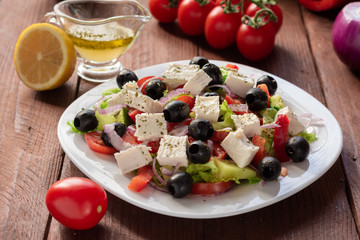 Greek salad with fresh cucumber , tomatoes, sweet pepper, lettuce, red onion, feta cheese and olives with olive oil. Healthy diet