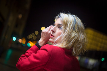 Street Style. A young sexy blonde woman in a red blazer with the night lights in the city