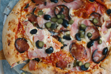 slice of pizza with hum, sausage,cucumber, olives onion and cheese crust close up photo
