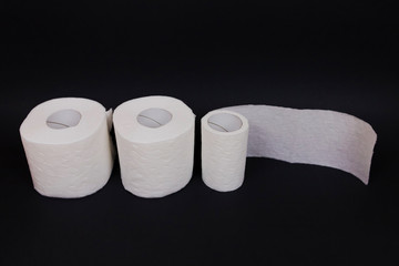 Three rolls of toilet paper on black background.