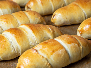Close-up of sausages baked in dough on a baking sheet. Side view