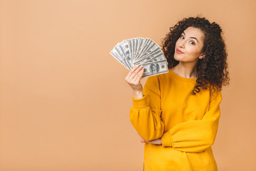 Portrait of a cheerful young woman holding money banknotes and celebrating isolated over beige background. - 331045337