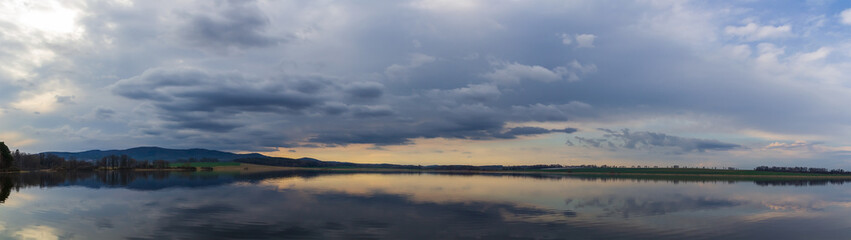Panoramic view to pond with dramatic overcast sky. Nice reflection in water, Czech landscape