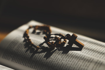 03/17/2020 Kiev, Ukraine: Catholic rosary and laptop lying on the table with a woman working at a computer and praying
