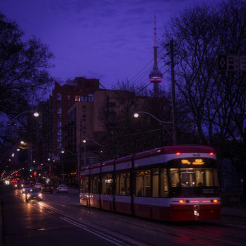 A streetcar on King street in Old Toronto district with cars, traffic lights, and street cars tracks glimmering in the darkness